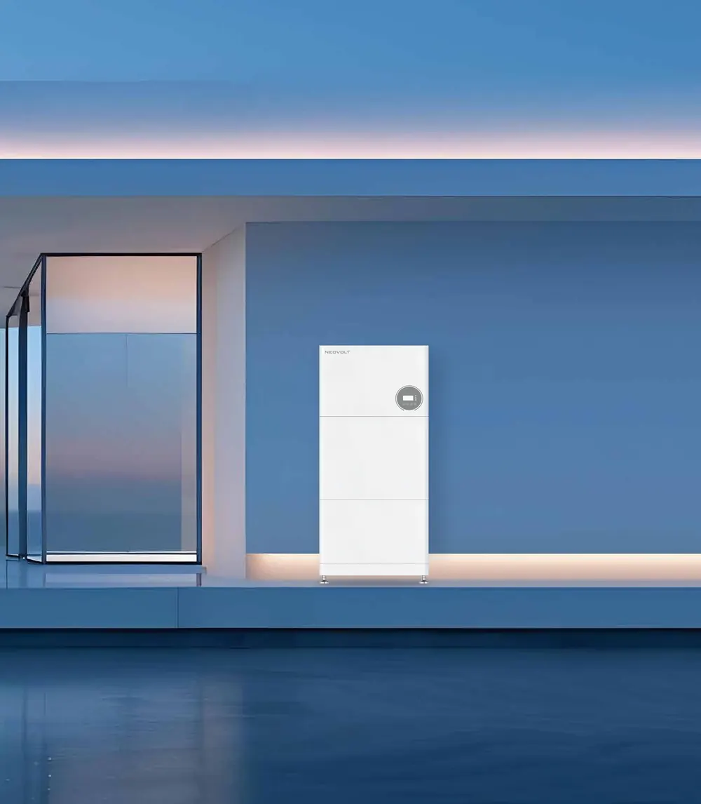 A white NEOVOLT battery stack against the wall of a modern house at dusk, with a warm strip of light along the wall behind it.
